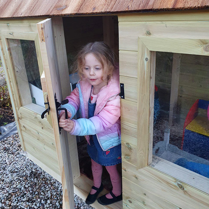 A Kid in a Customisable wooden playhouse for kids in garden - Artisan Deco - Made in the UK